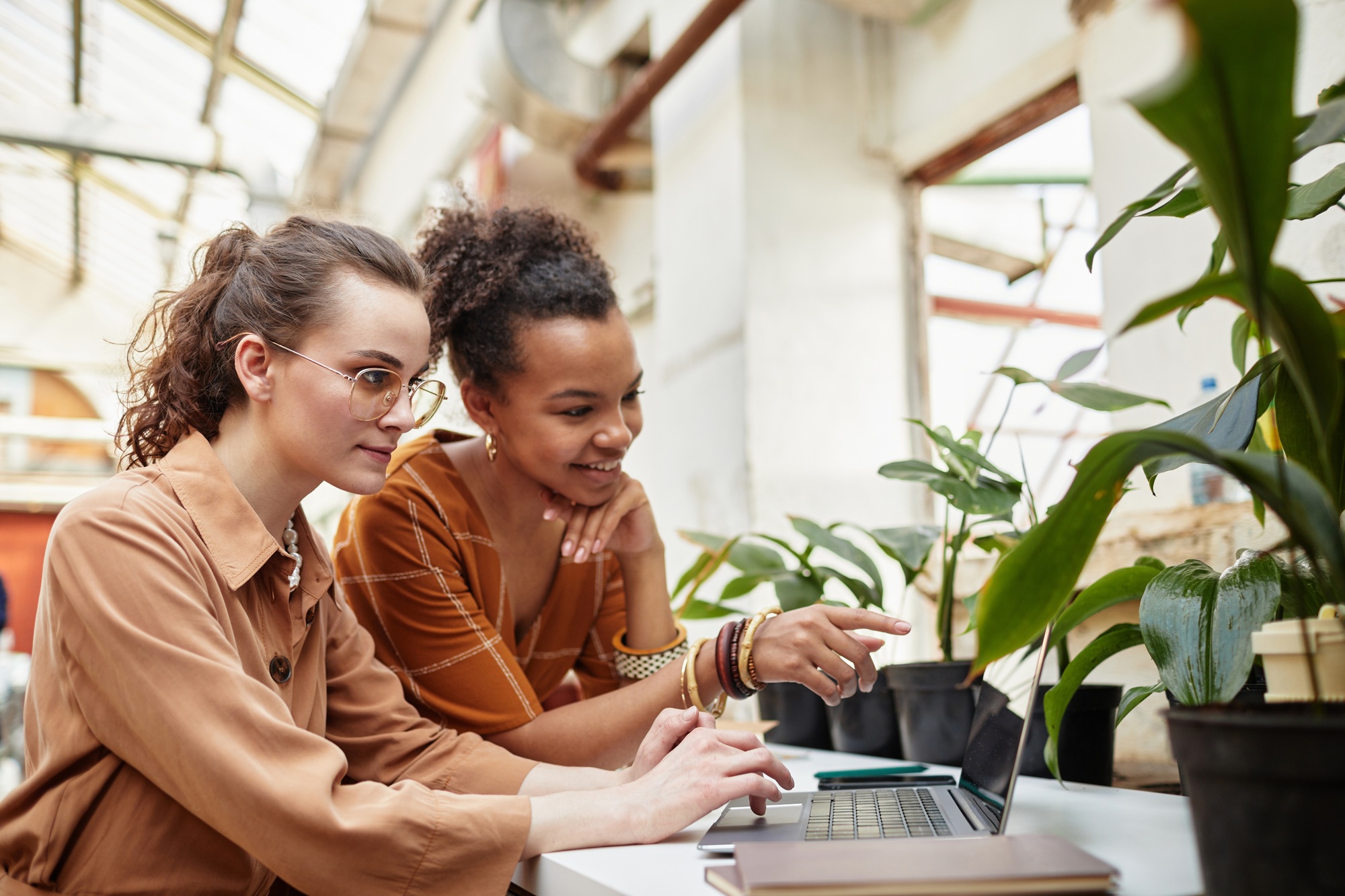 Two young female designers discussing online project of floral shop interior