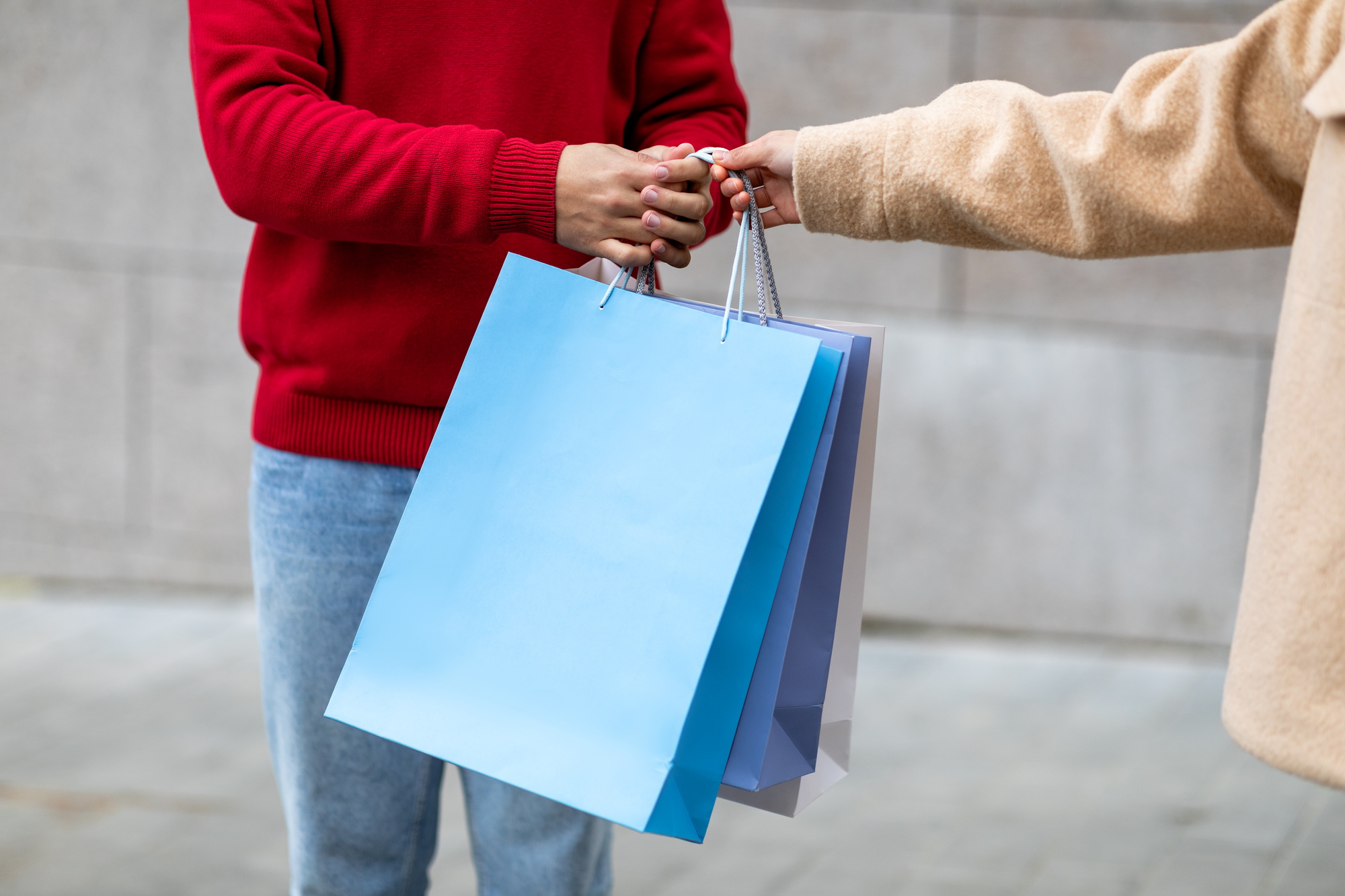 Unrecognizable man and woman holding bright shopper bags outdoors, mockup for your brand logo design
