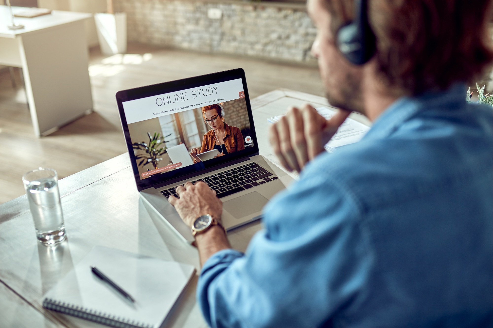Unrecognizable man choosing online study program while using laptop.