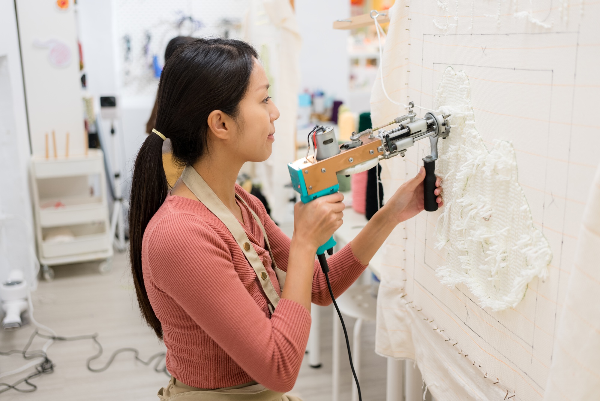 Woman make carpet with the tufting gun