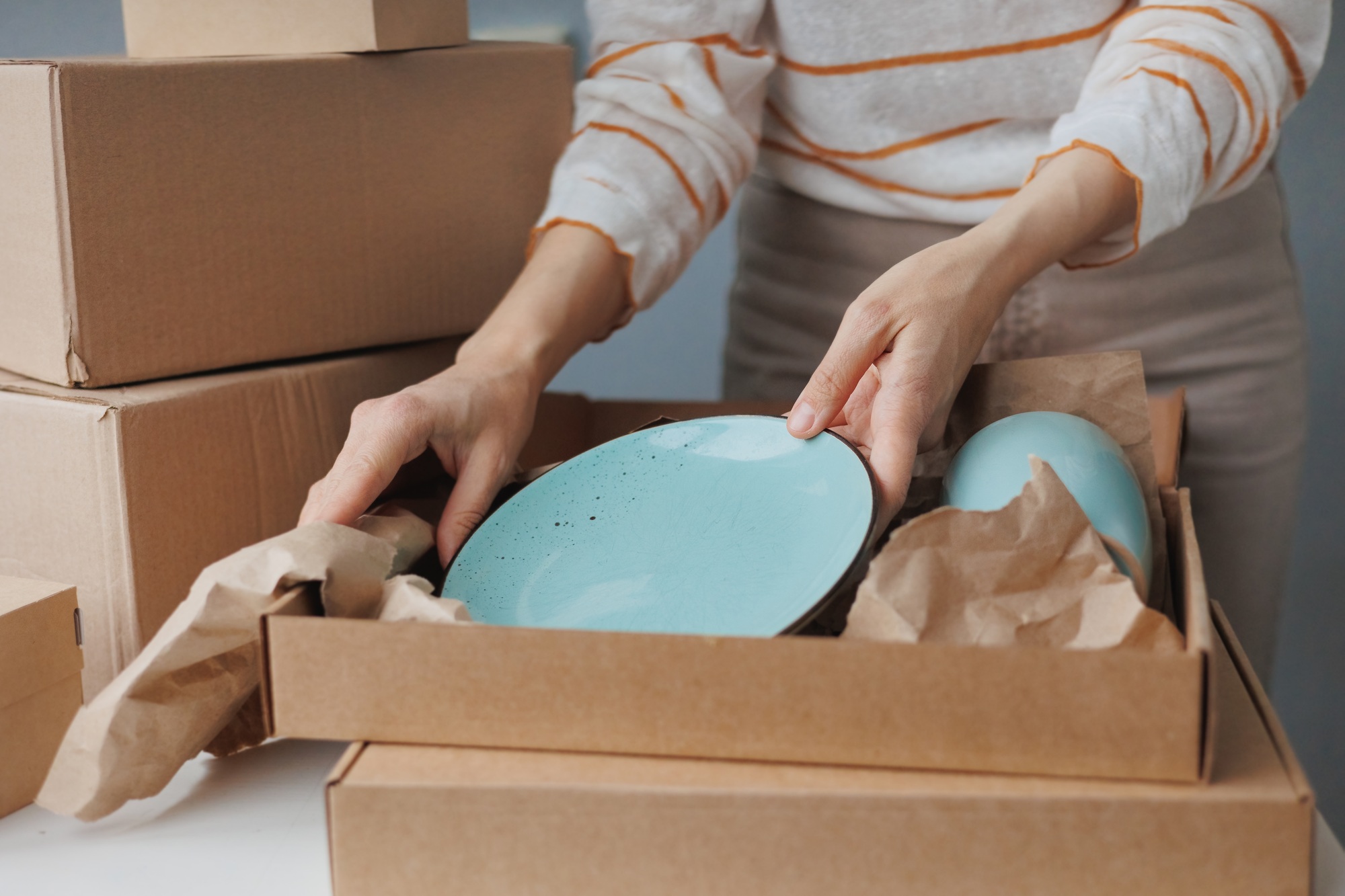 woman packs handmade plates into boxes. small business and entrepreneurship. a business woman sends