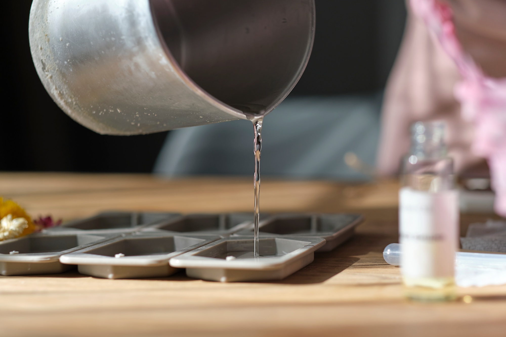 woman pours beeswax into a silicone mold to make candles