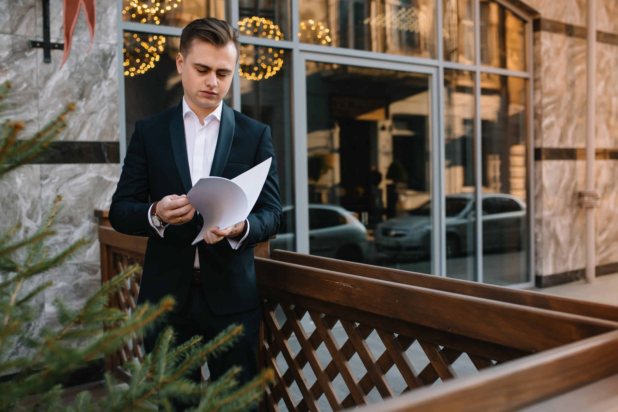 Young business man with documents and mobile phone near of modern building.