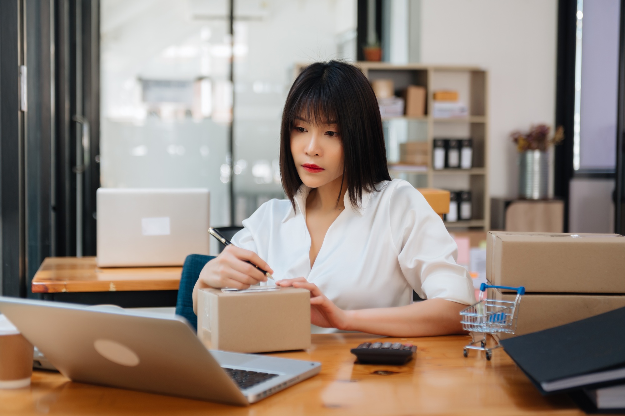 Young business owner woman prepare parcel box and standing check online orders for deliver