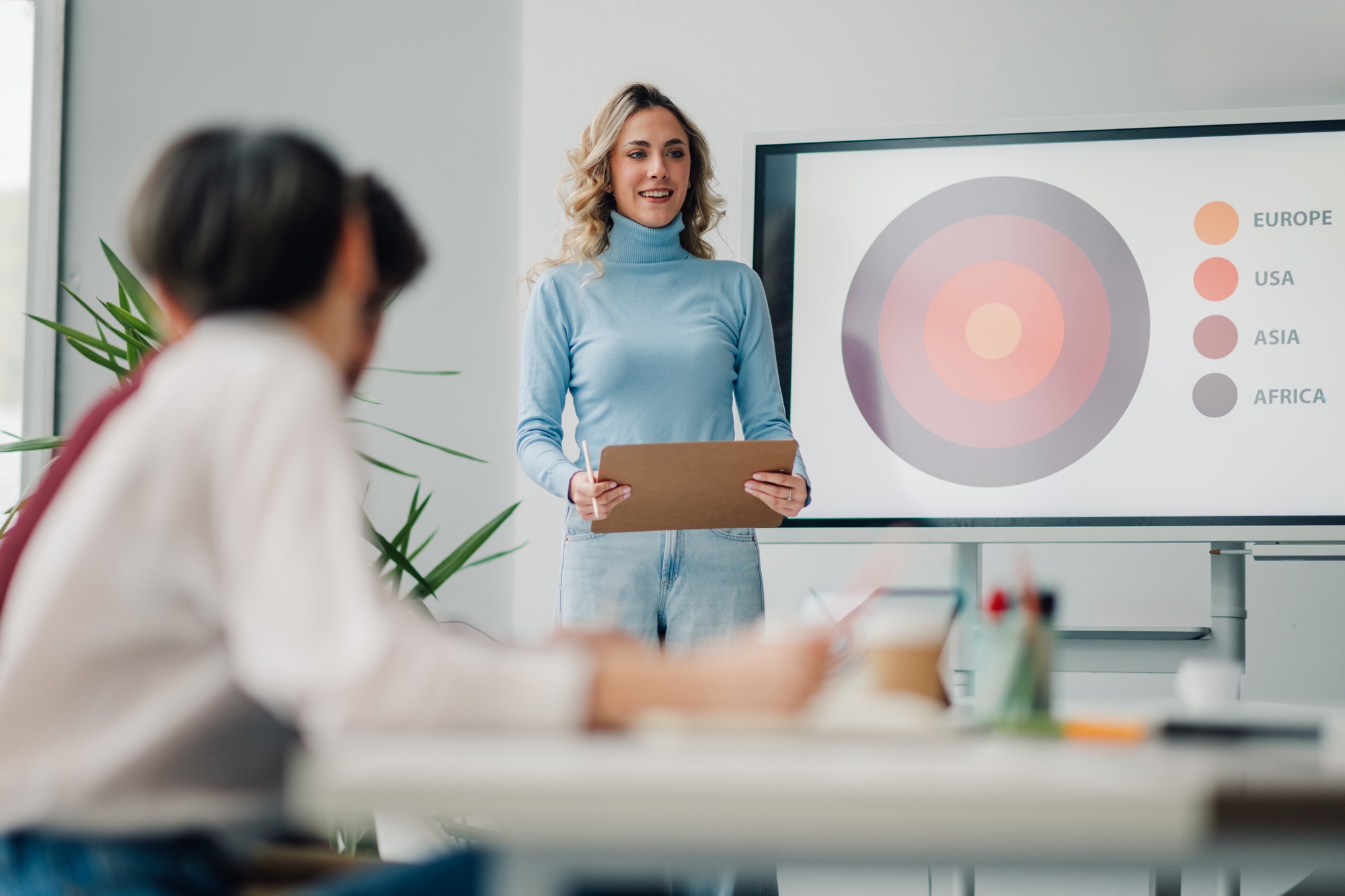 Young businesswoman leading a meeting, presenting sales data to her colleagues