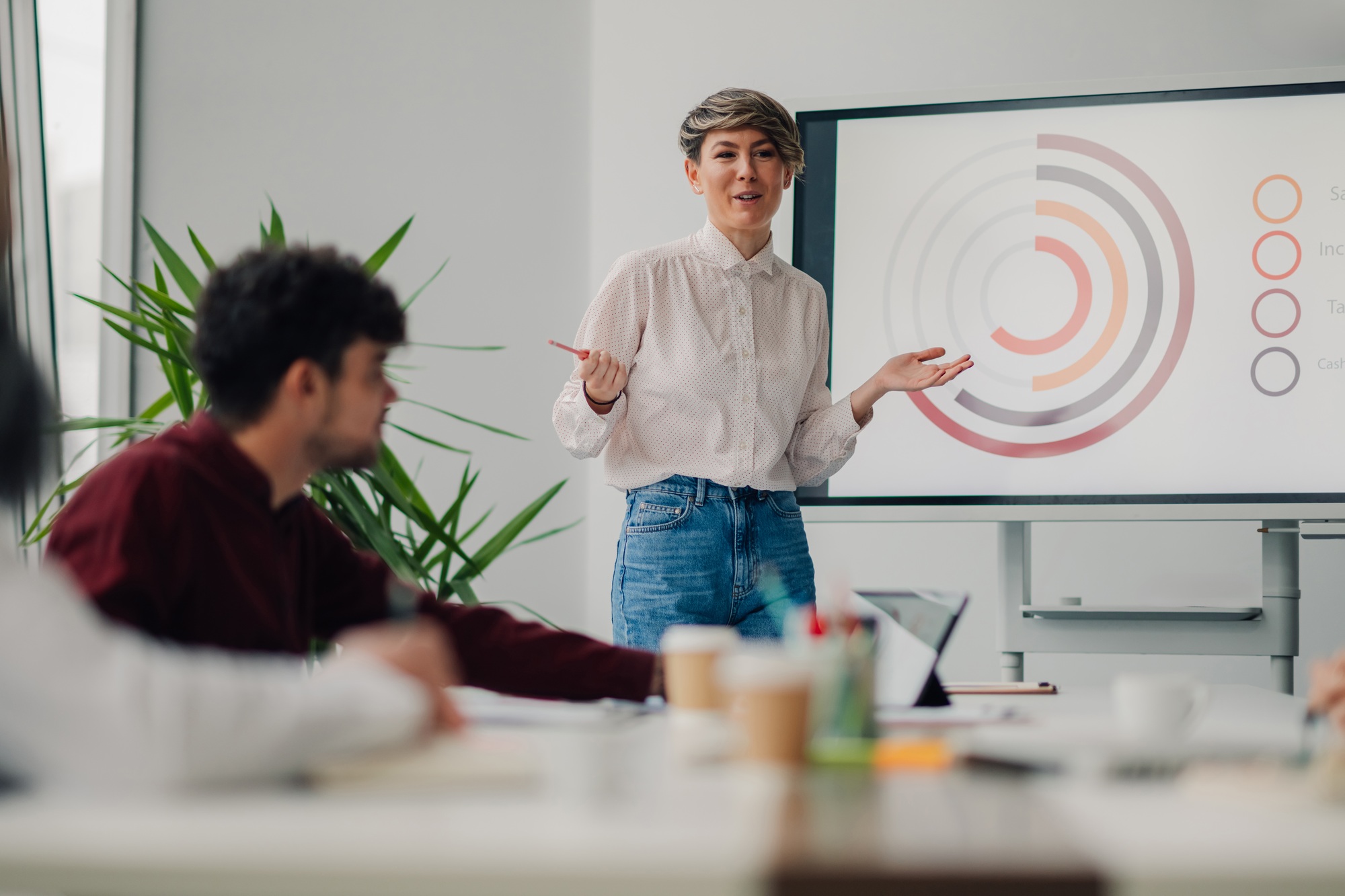 Young businesswoman presenting marketing data on a whiteboard during a meeting