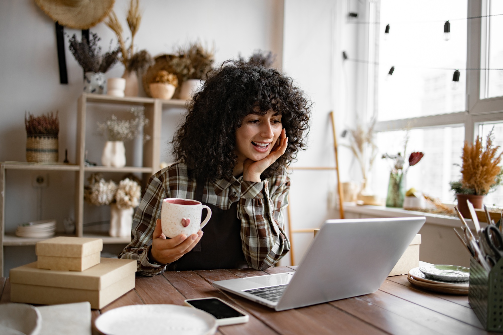 Young Caucasian woman potter happy with online sale of mug.