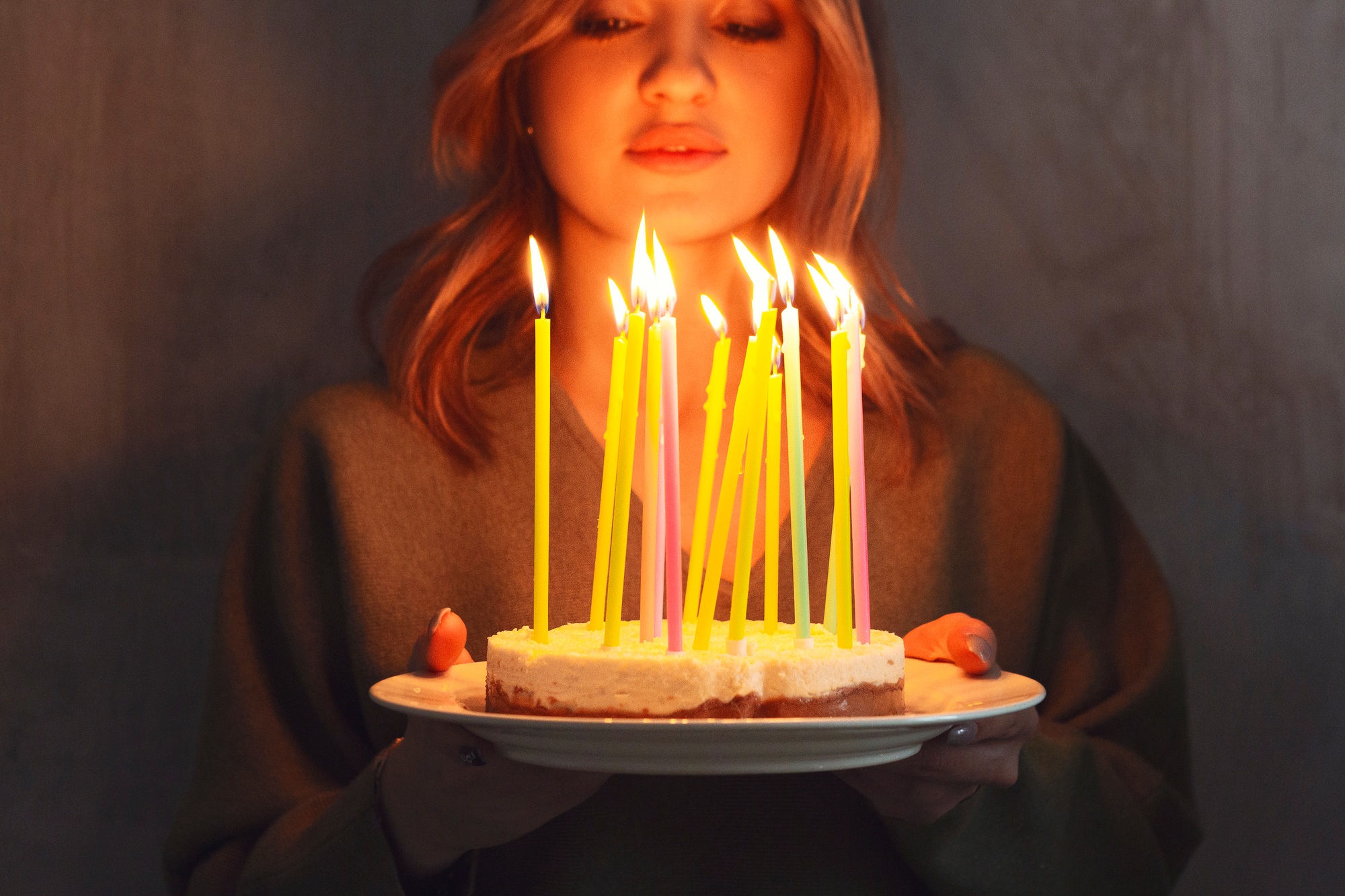 Young smiling woman holding homemade birthday cake pie with burning candles