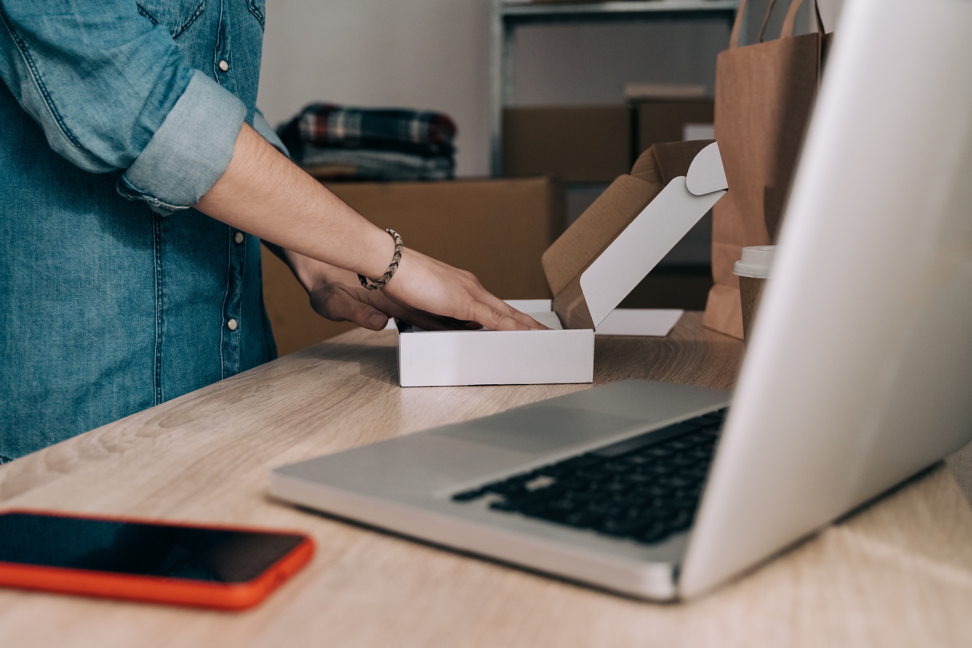 Young warehouse worker packing ecommerce shipping order for online delivery - Focus on woman hand