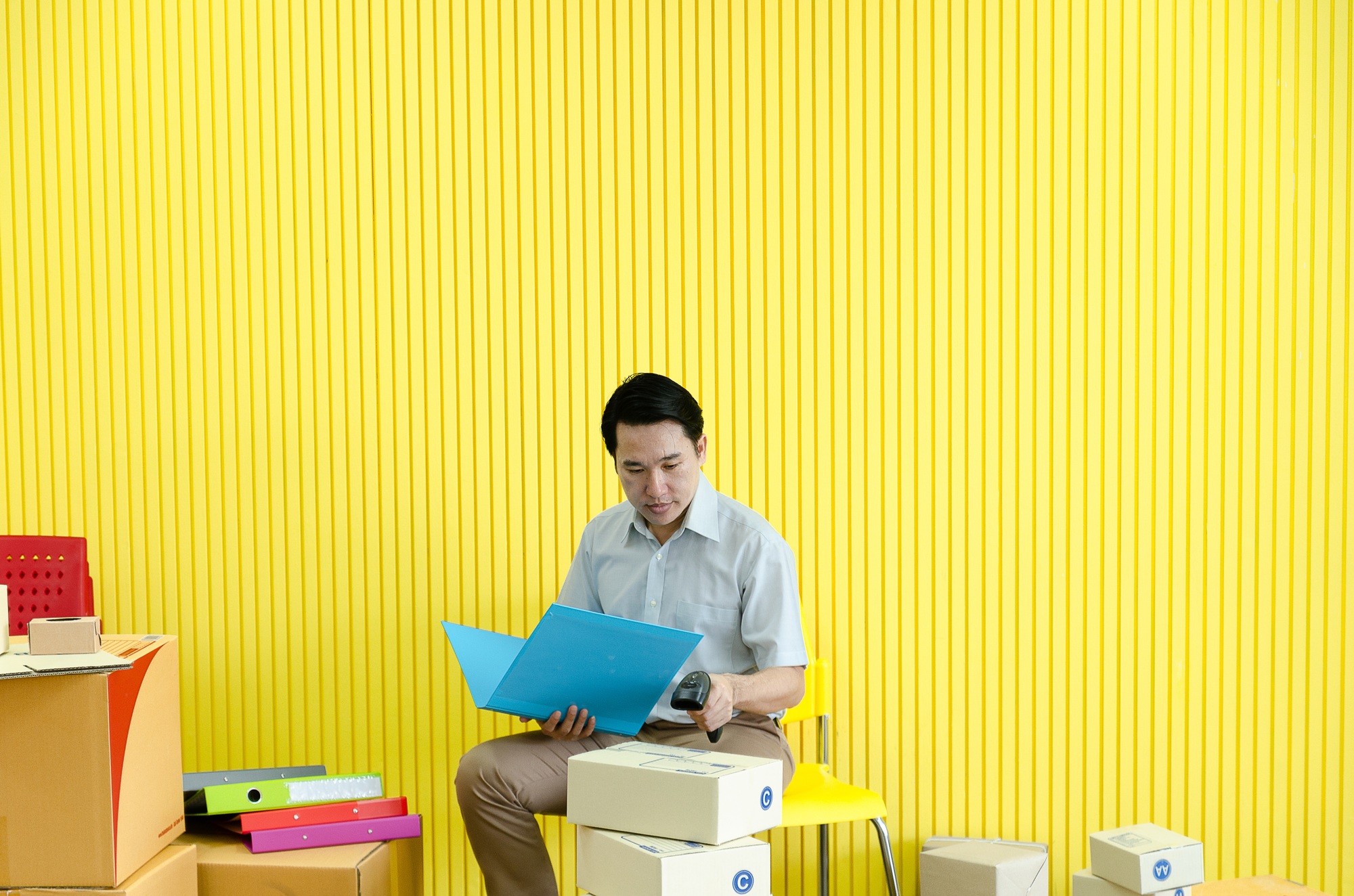 Asian small businessman checks inventory and prepares it for delivery to customer,yellow background