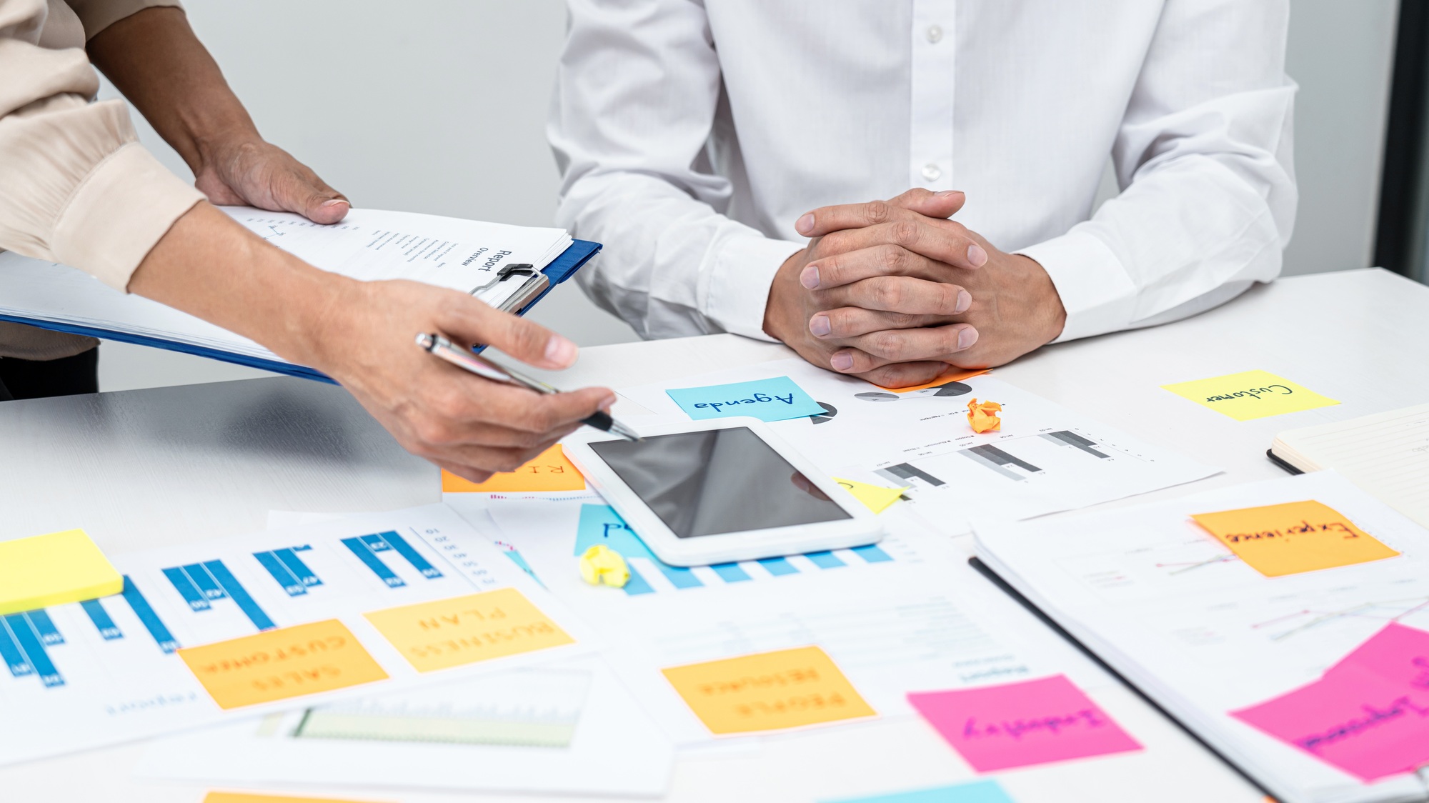 Businesswoman holding document and pointing data on tablet to explaining business report