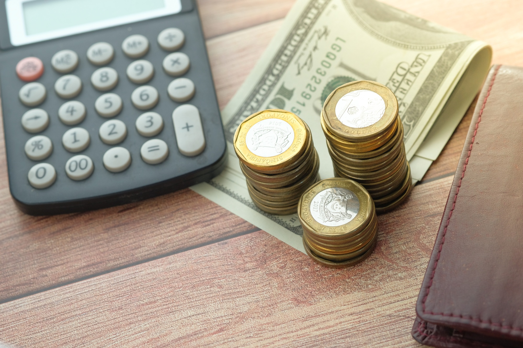 Finance Concept A Calculator, Various Coins, and Money on a Wooden Desk Surface