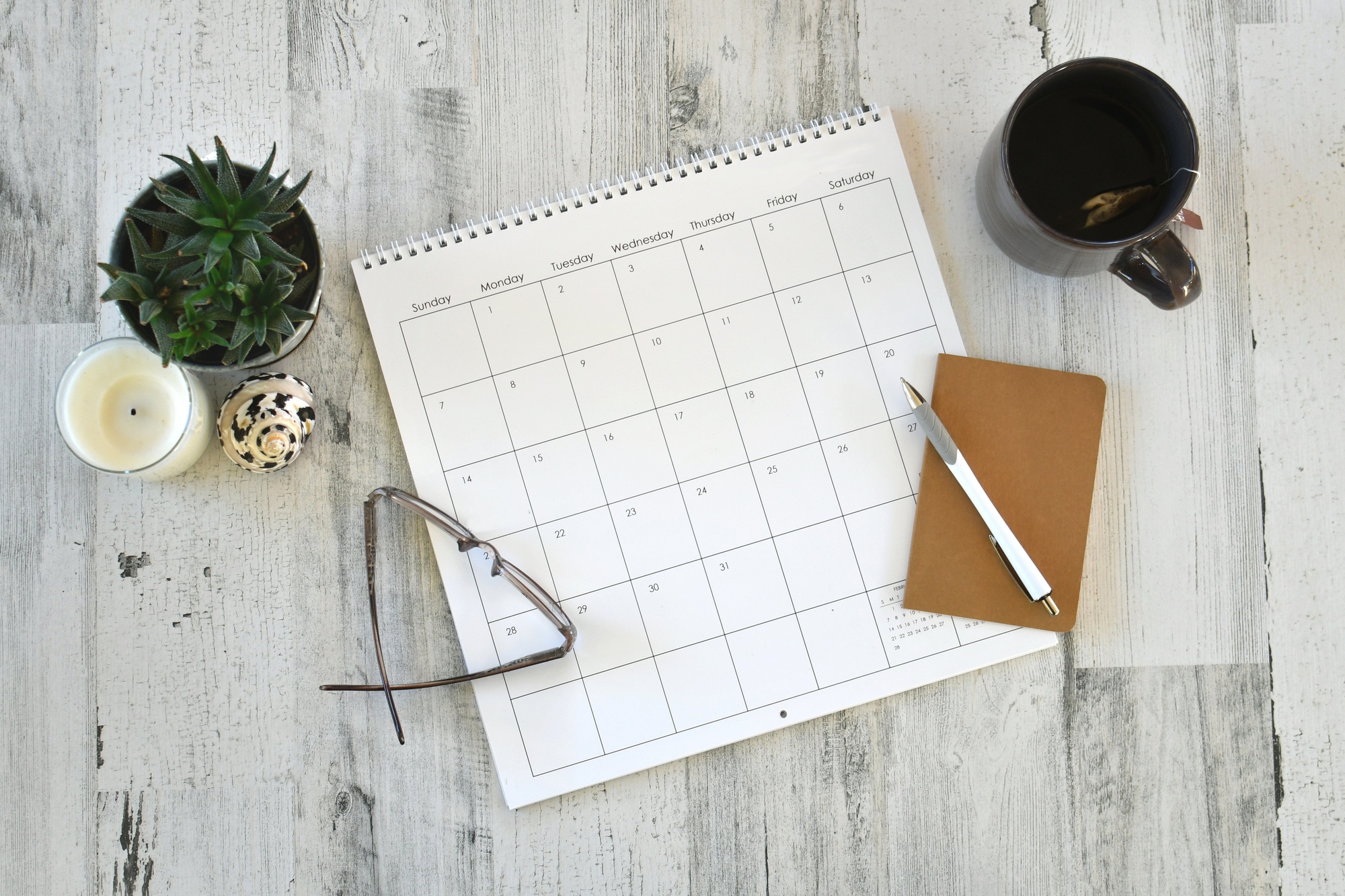 Overhead flat lay view of calendar, notebook scheduling work personal appointments - blank no year