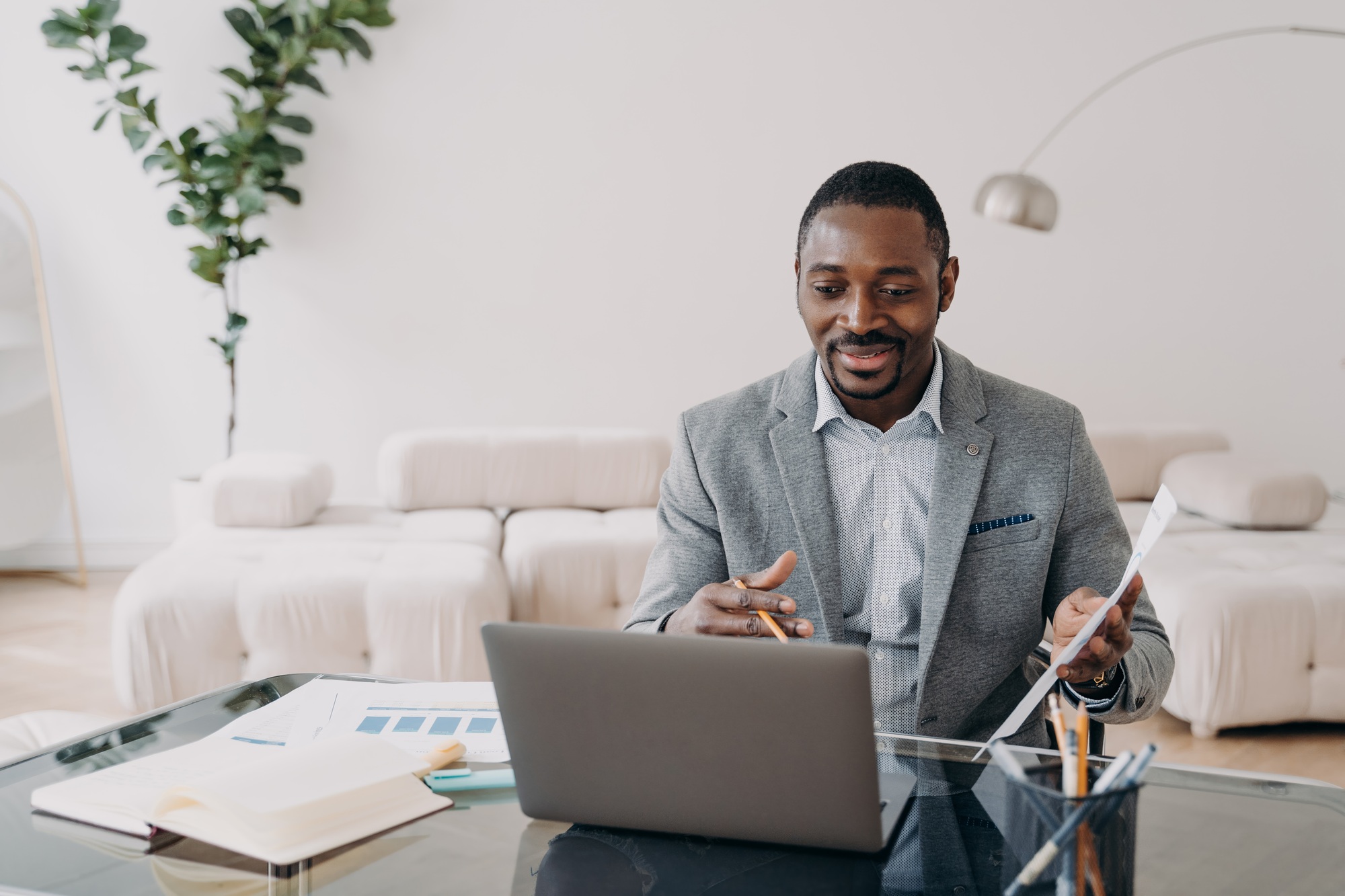 Relaxed professional man going over financial charts on his laptop in a bright home office.