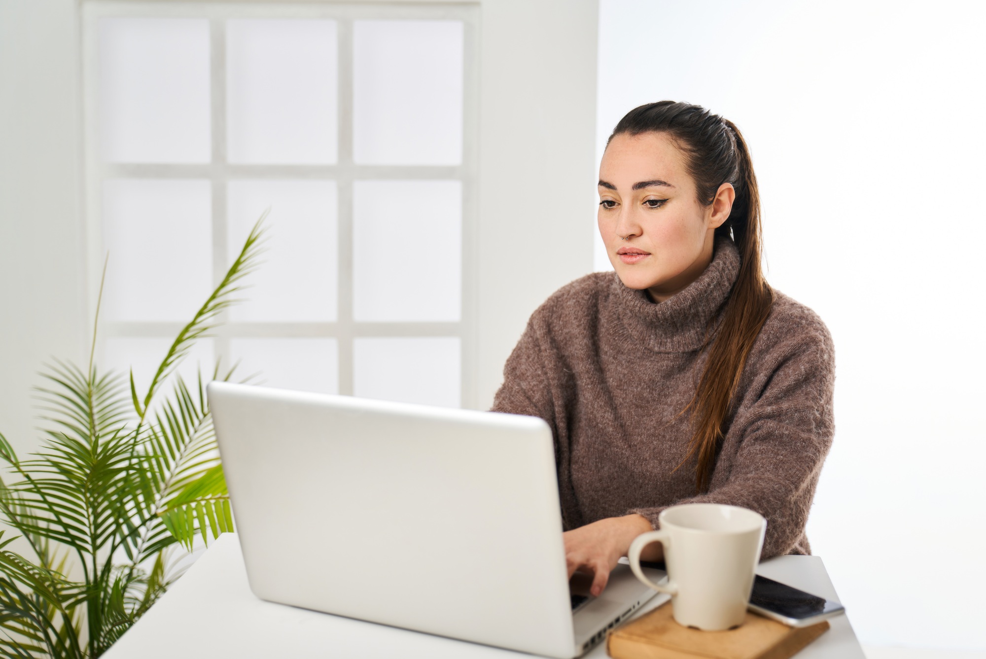 a smiling woman typing on a laptop in the office