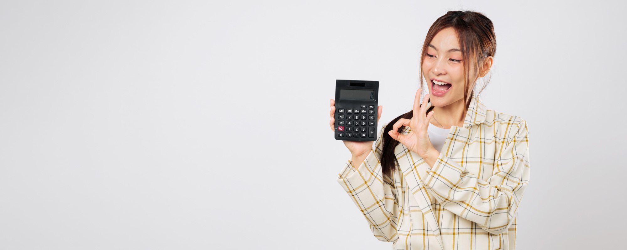 Business woman holding calculator and pointing to a second calculator with OK gesture