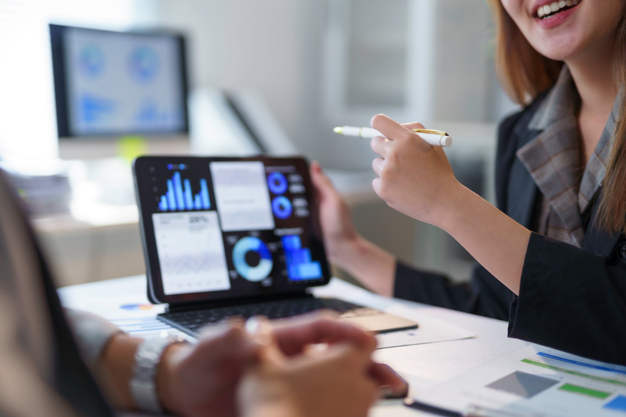 Businesswoman pointing at tablet showing charts and graphs during a meeting