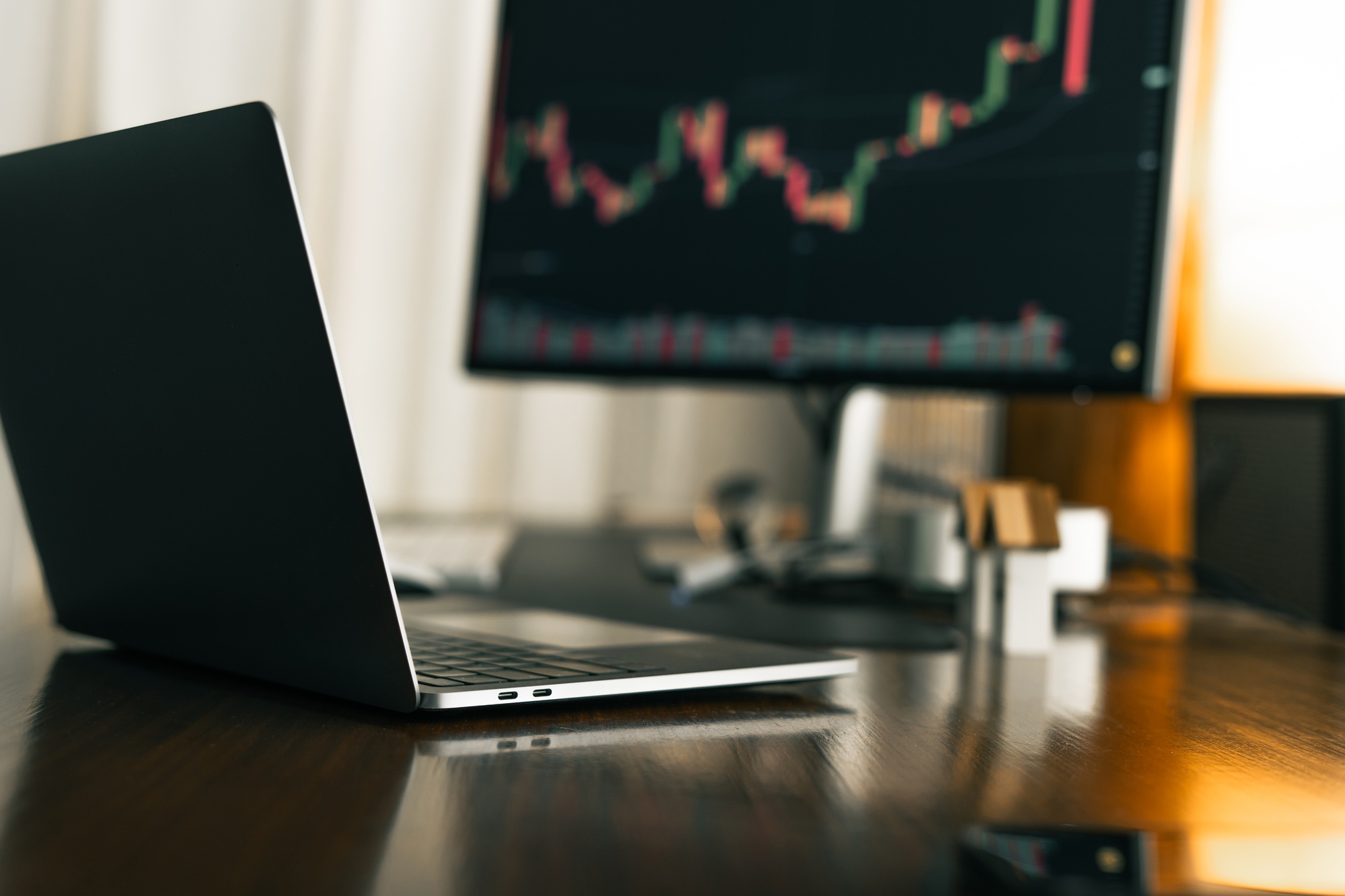 Home office desk background with laptop and stock chart display.