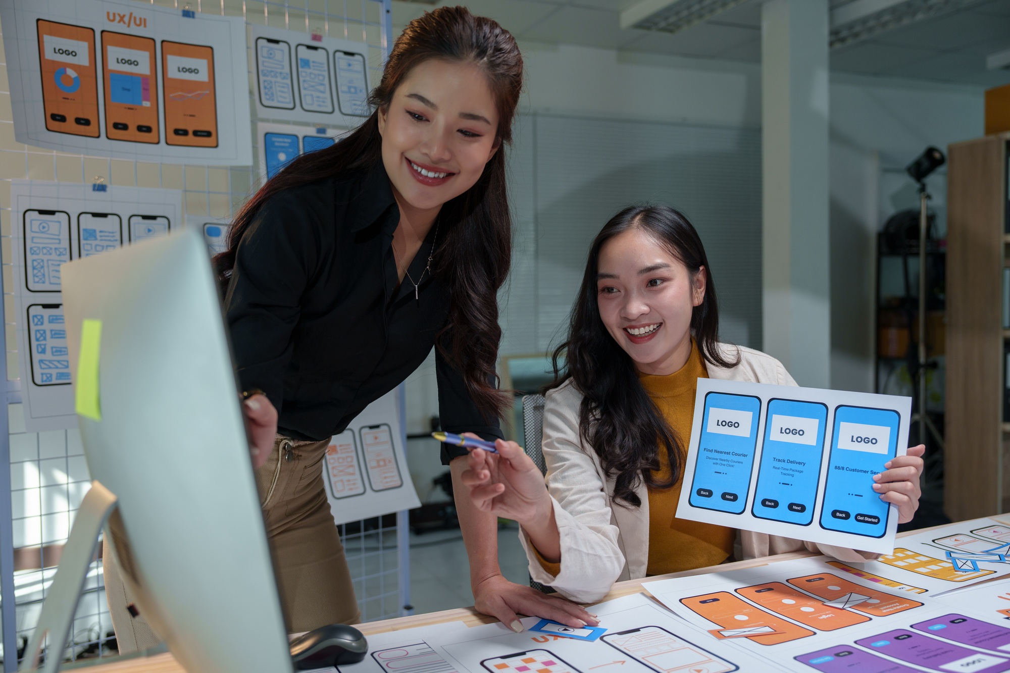 Two happy female web designers are collaborating on a new website's user interface and user experien