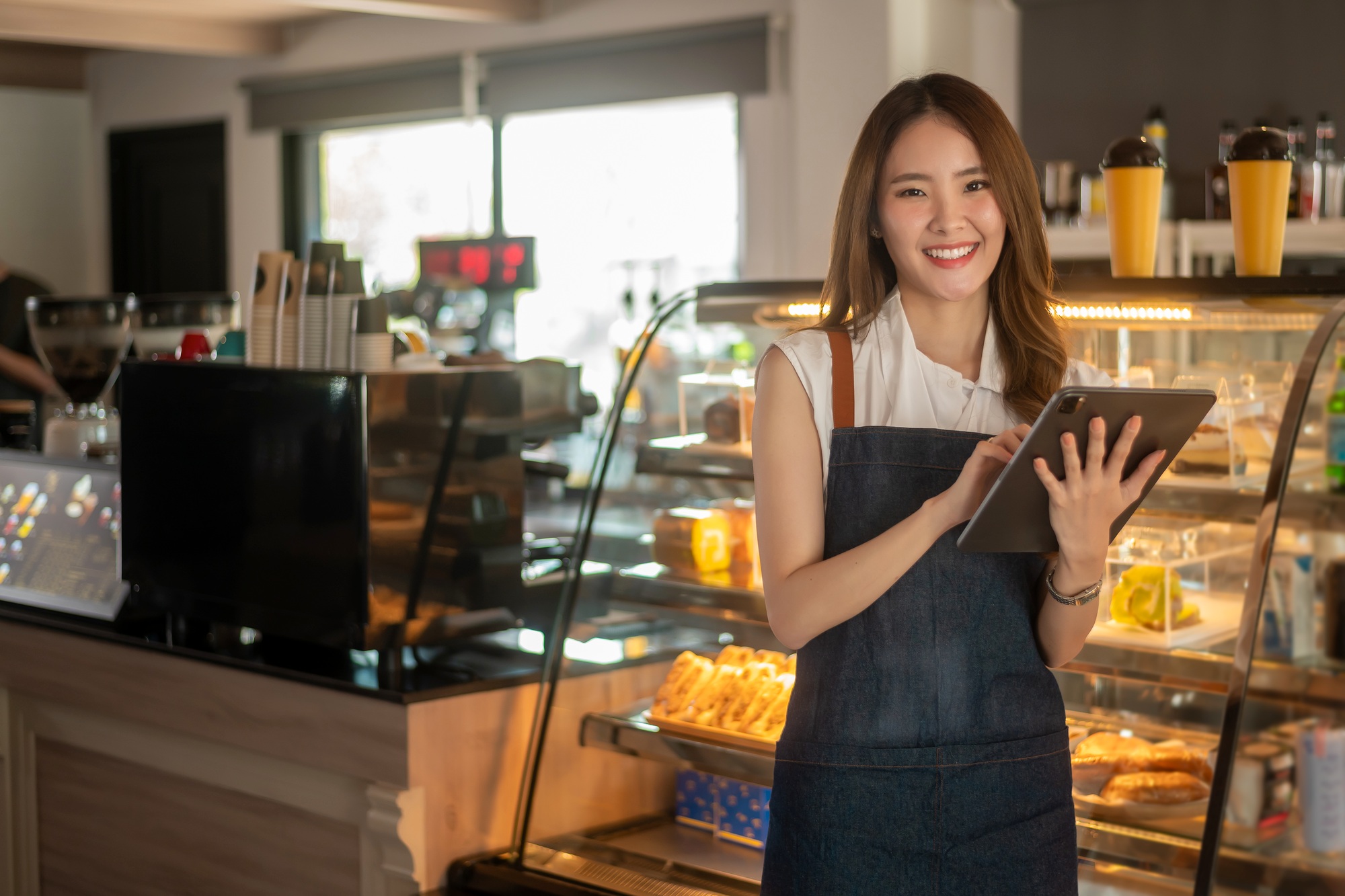 Woman entrepreneur using tablet checking stock in modern coffee shop