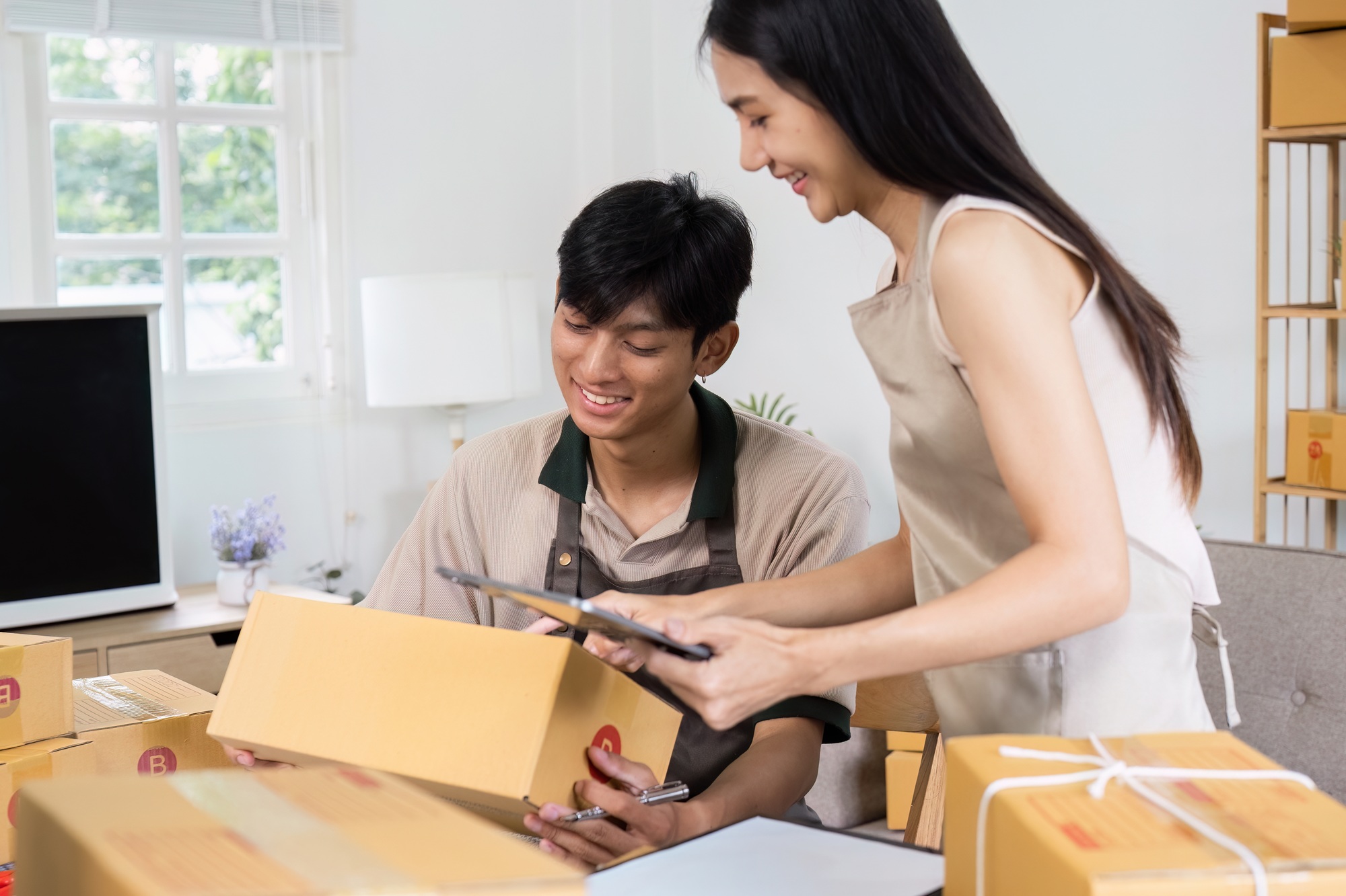 Young Entrepreneurs Packing Boxes for Online Orders in a Home Office Setting